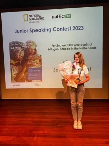 Iris Freriksen van Pius X College poseert met bloemen en prijzen na het behalen van de tweede plaats bij de Junior Speaking Contest 2023 in Amersfoort